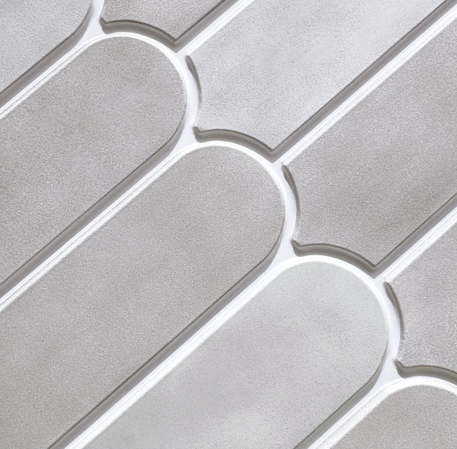 A close-up of light gray textured wall tiles with a repeating curved, elongated oval pattern and white grout lines.